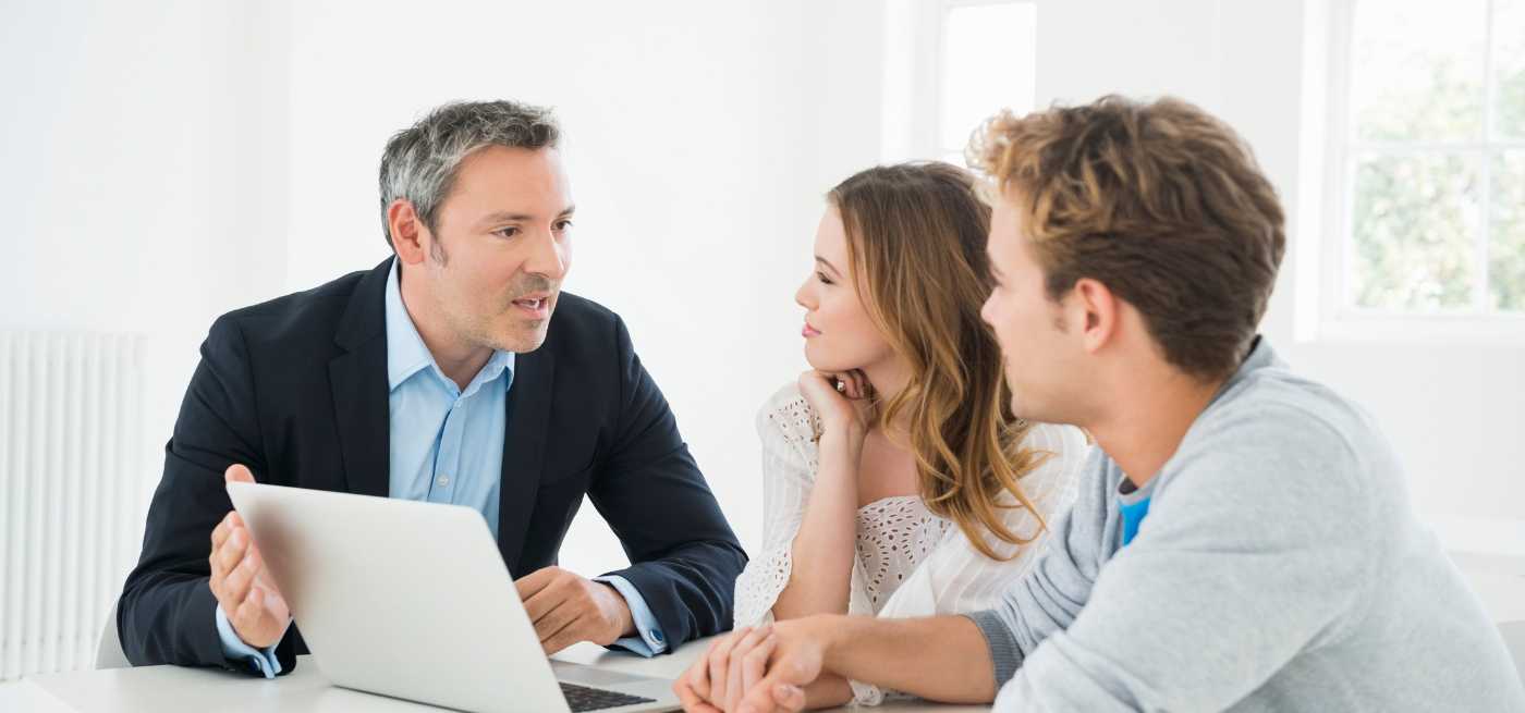 Consultor a explicar informação no portátil a um casal atento durante uma reunião